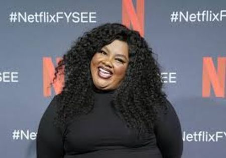 Nicole Byer in a black top poses a picture at a Netflix event.